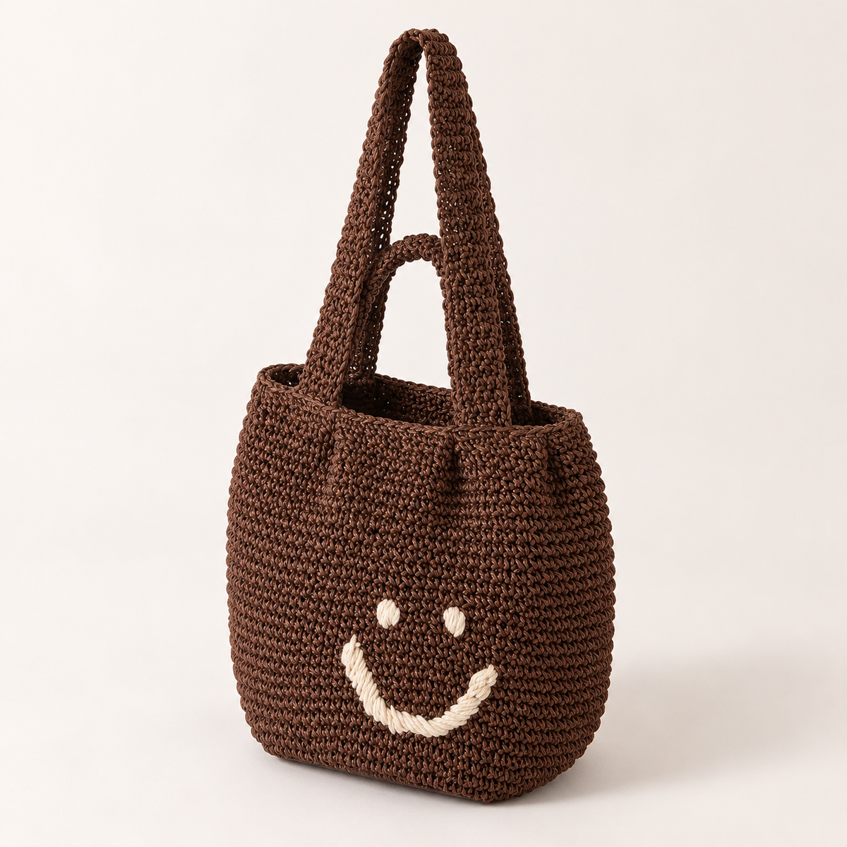Smiley Woven Shoulder Bag, angled view showing a stitched smiley face
