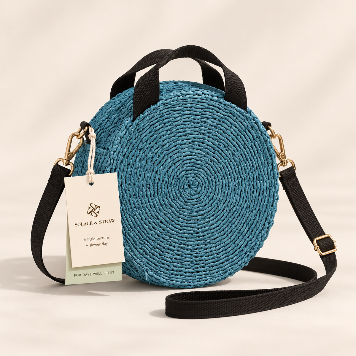 Round Woven Crossbody in slate blue with black straps, front view with a Solace & Straw hangtag