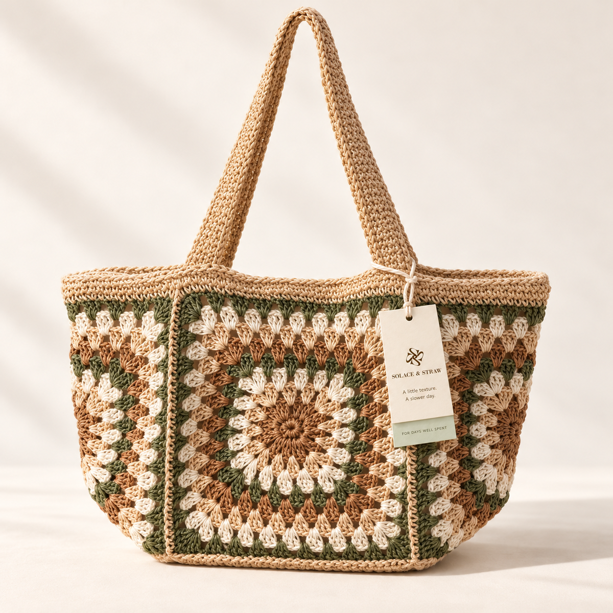 Garden Square Paper Woven Tote in green / cream / tan, front view with Solace & Straw hangtag