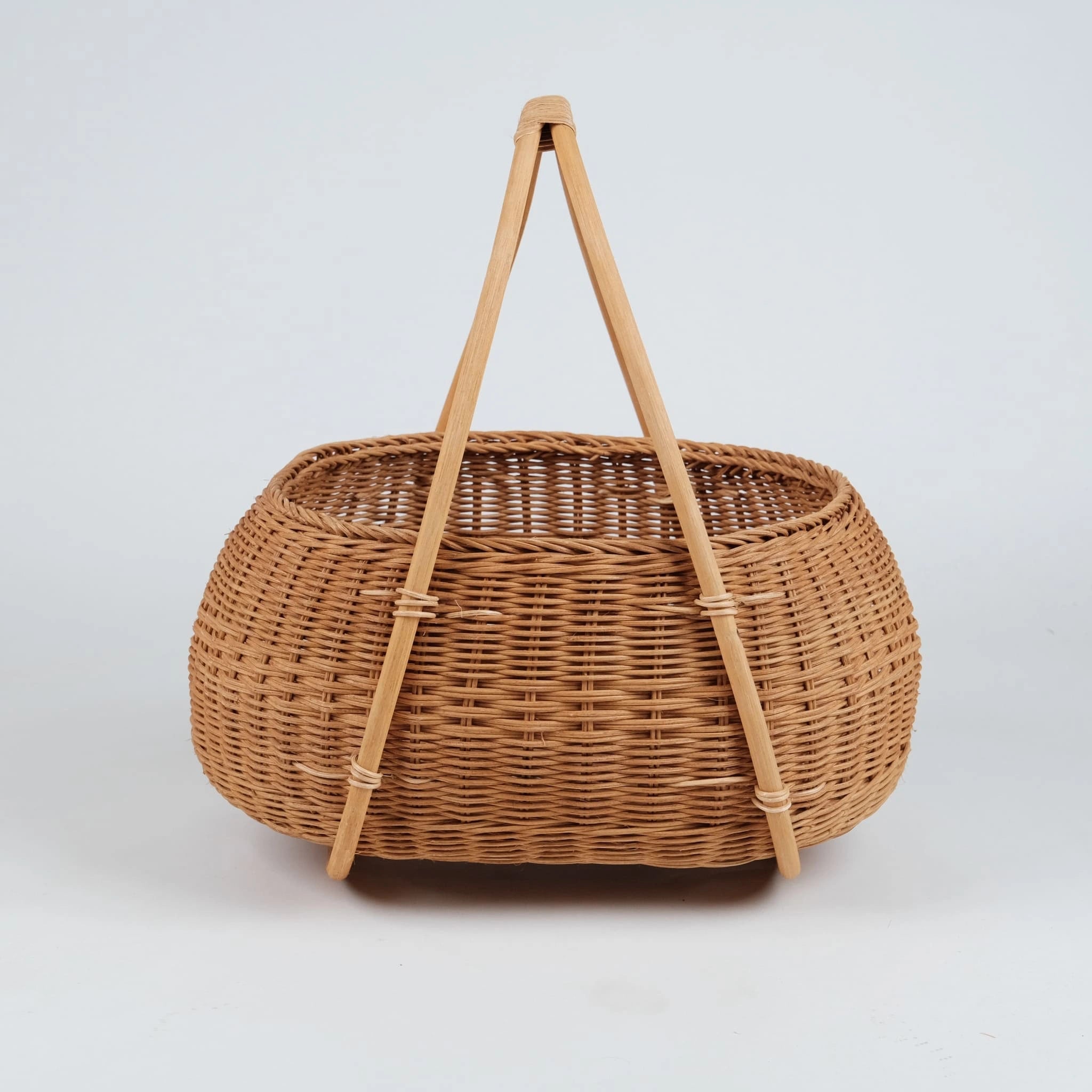 Nordic rattan picnic basket with A-frame wooden handles, 
natural honey tone, handwoven wicker, front view