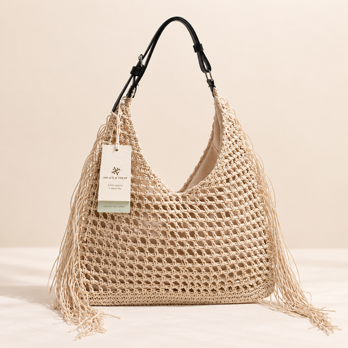 Tassel Woven Tote in cream with side fringe, front view with a Solace & Straw hangtag