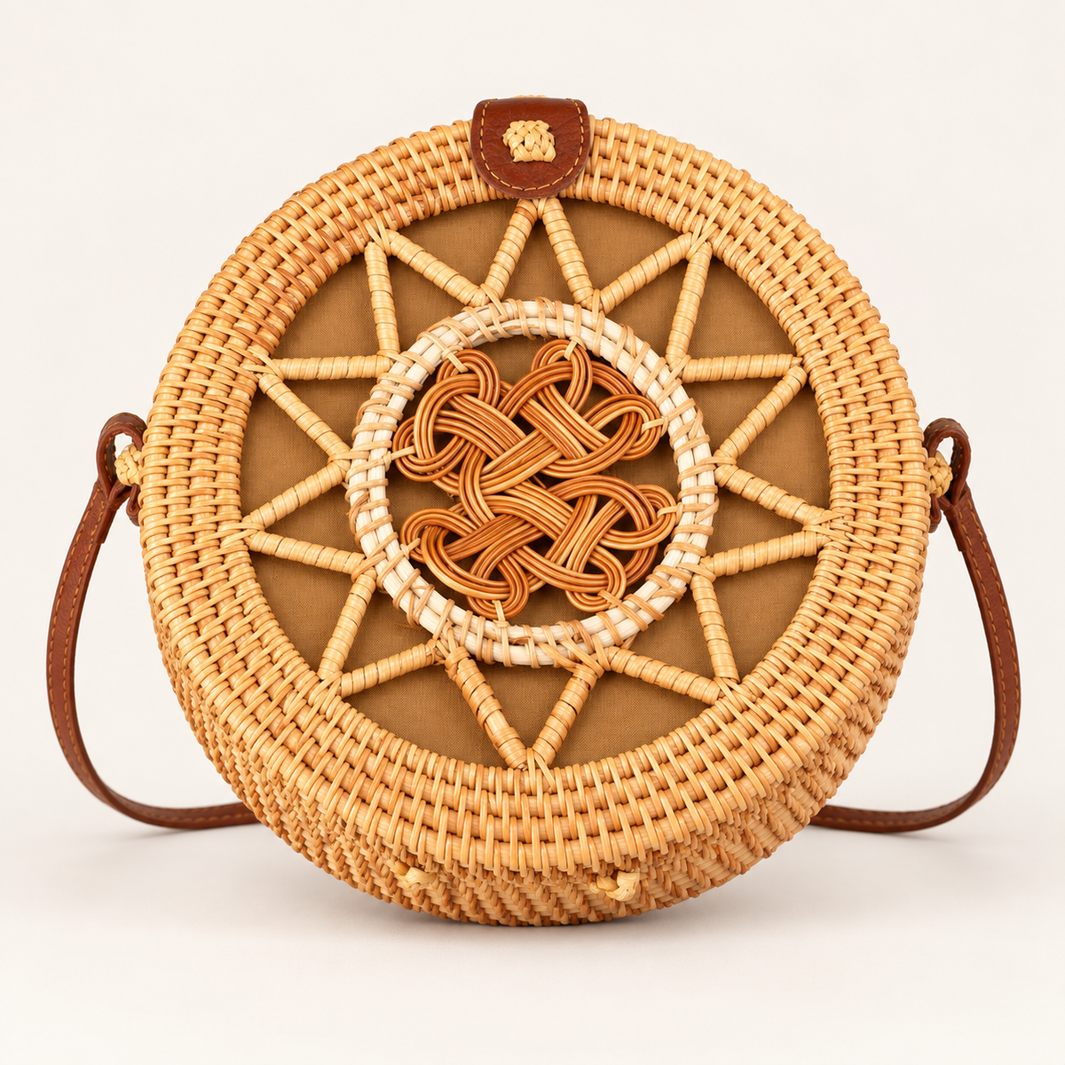 Round Rattan Crossbody in honey tan, front view with a central woven knot and brown shoulder strap