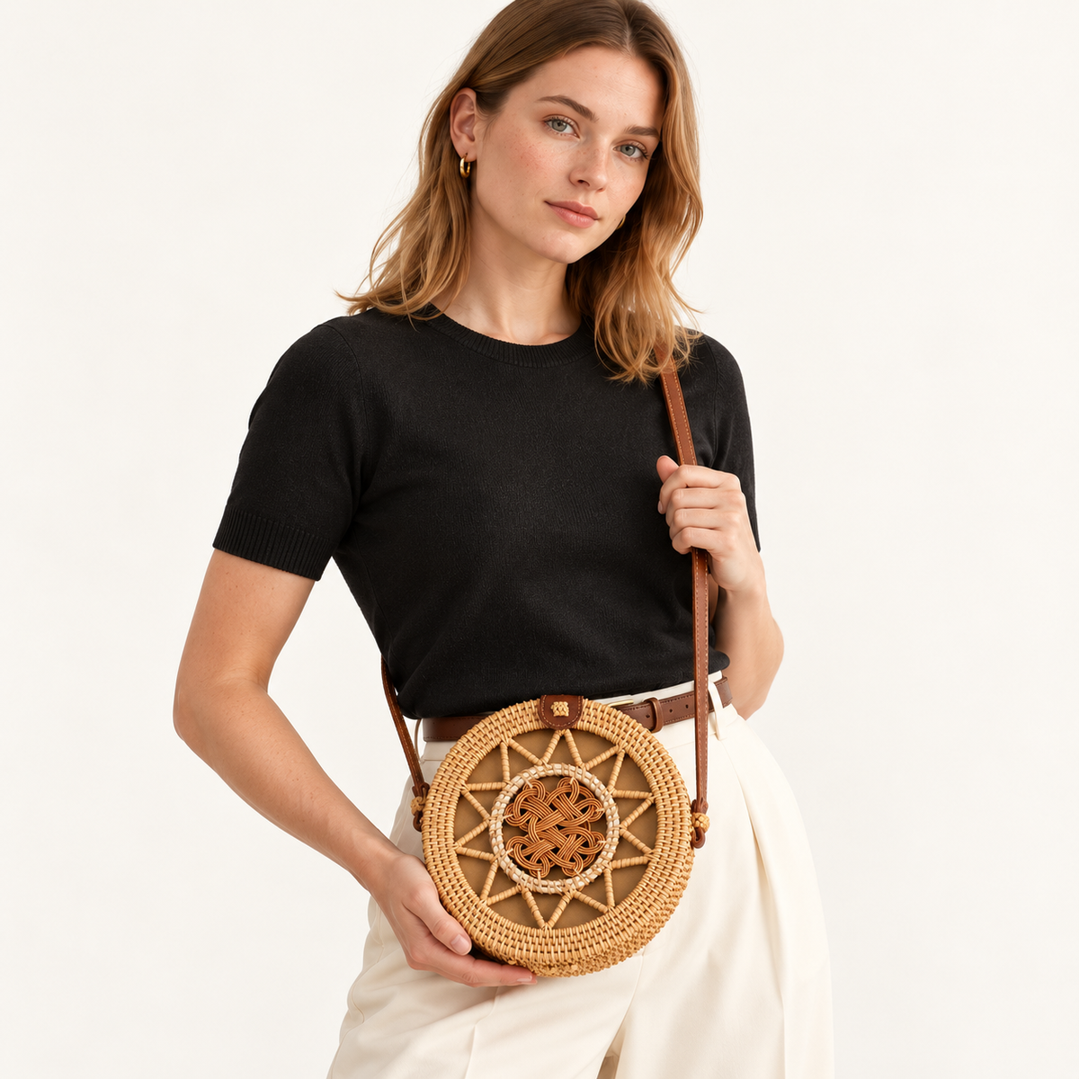 Woman carrying the Round Rattan Crossbody with a central woven knot and brown shoulder strap
