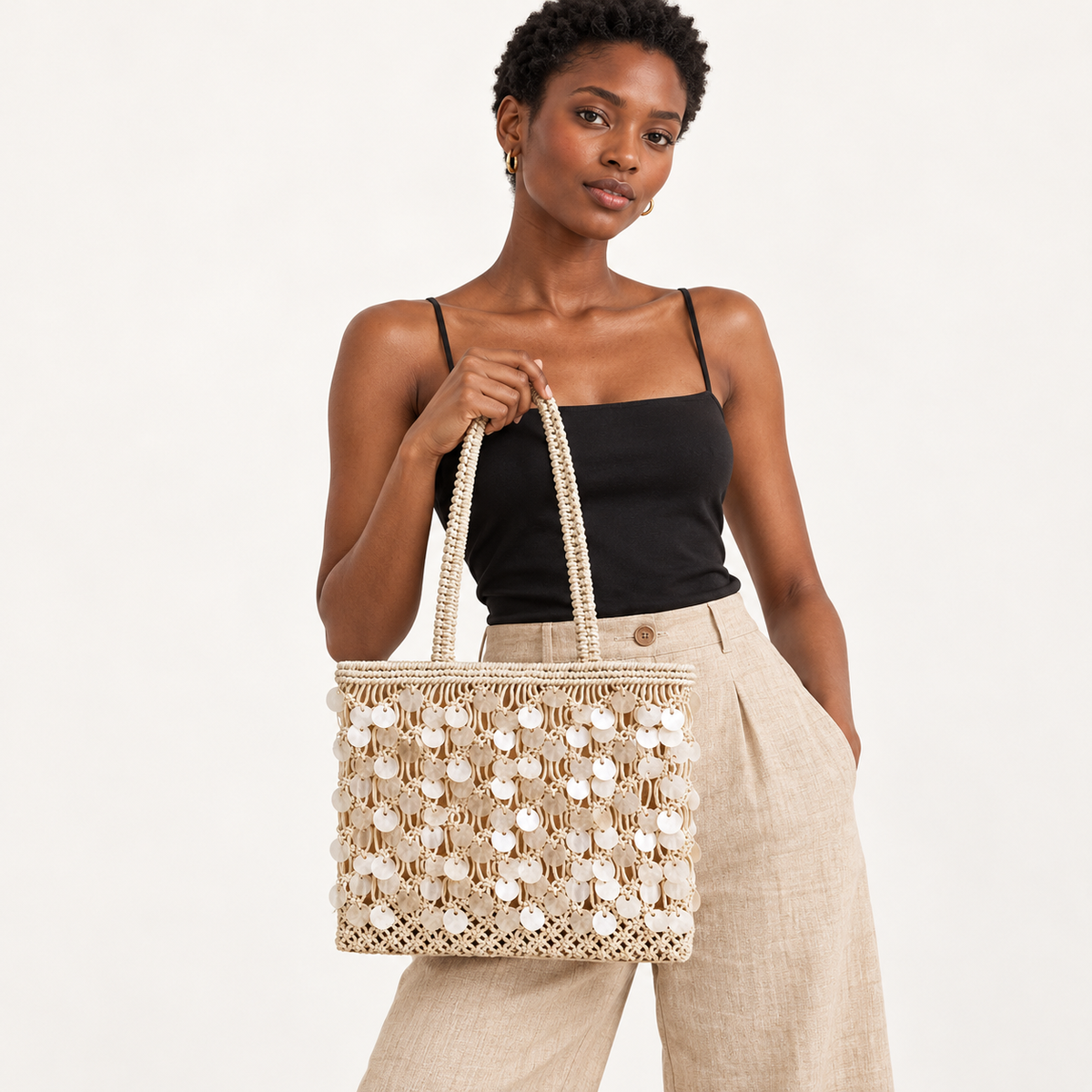 Woman carrying the Shell Detail Cotton Net Tote in ivory, studio styling