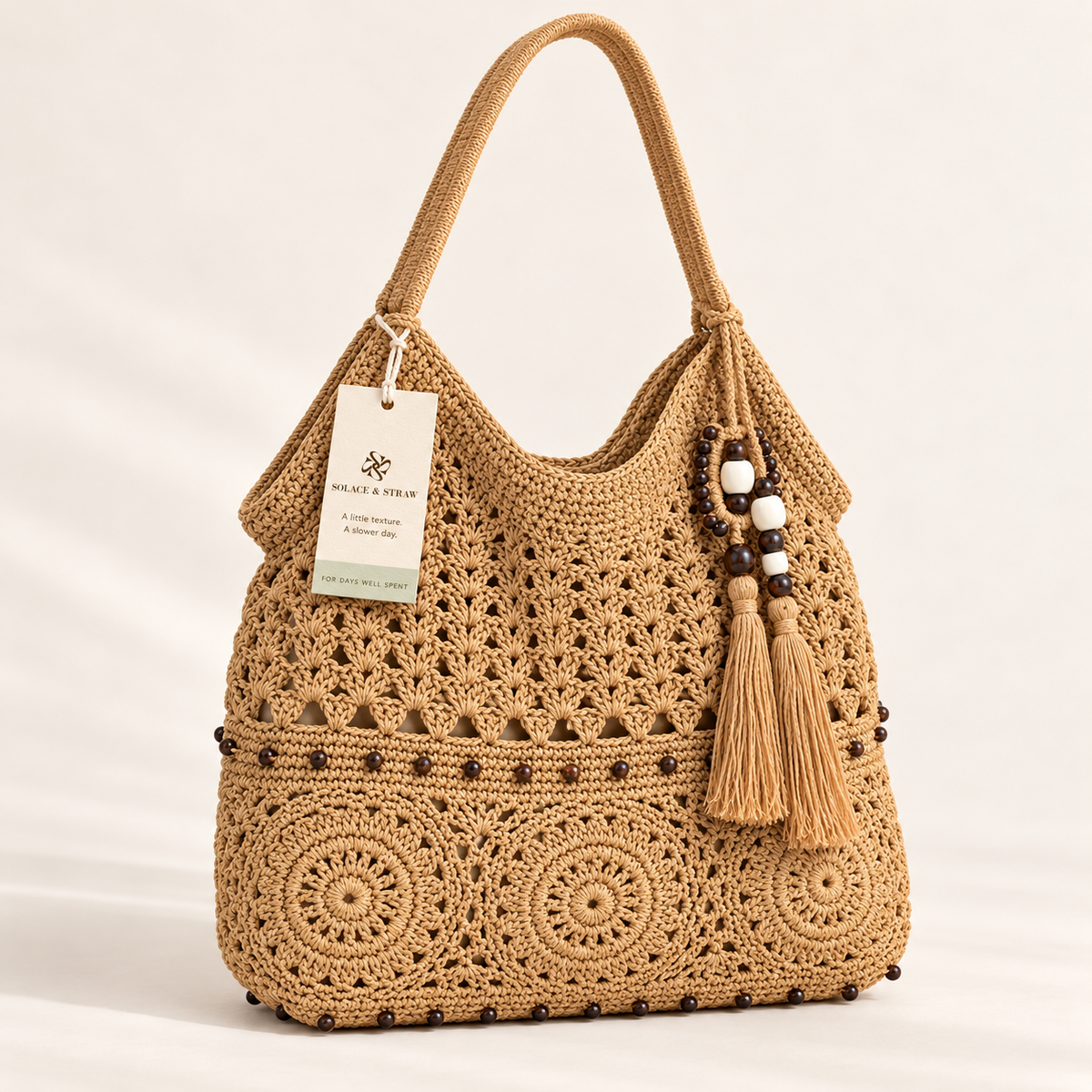 Floral Crochet Tassel Tote in tan, front view with Solace & Straw hangtag