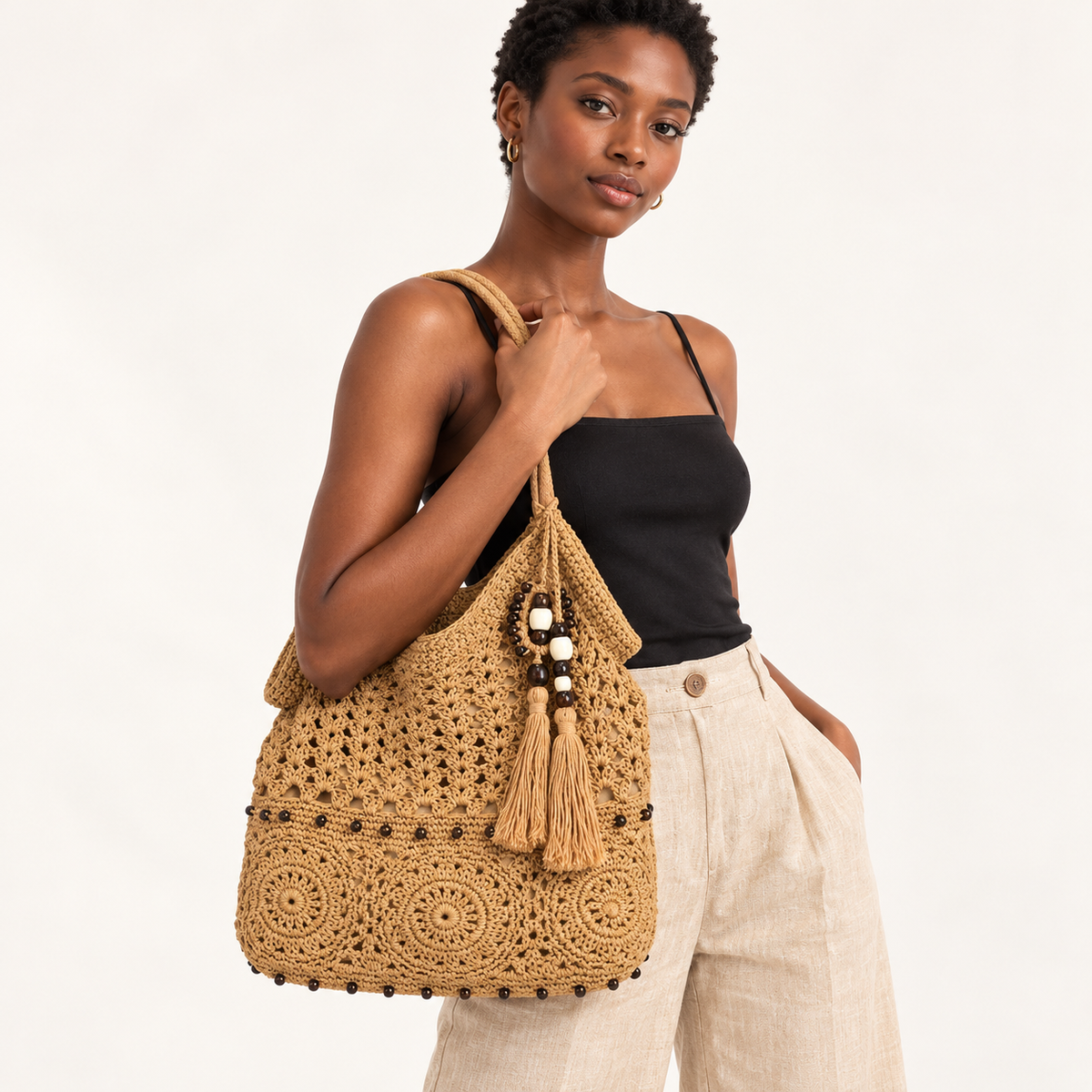 Woman carrying the Floral Crochet Tassel Tote in tan, studio styling