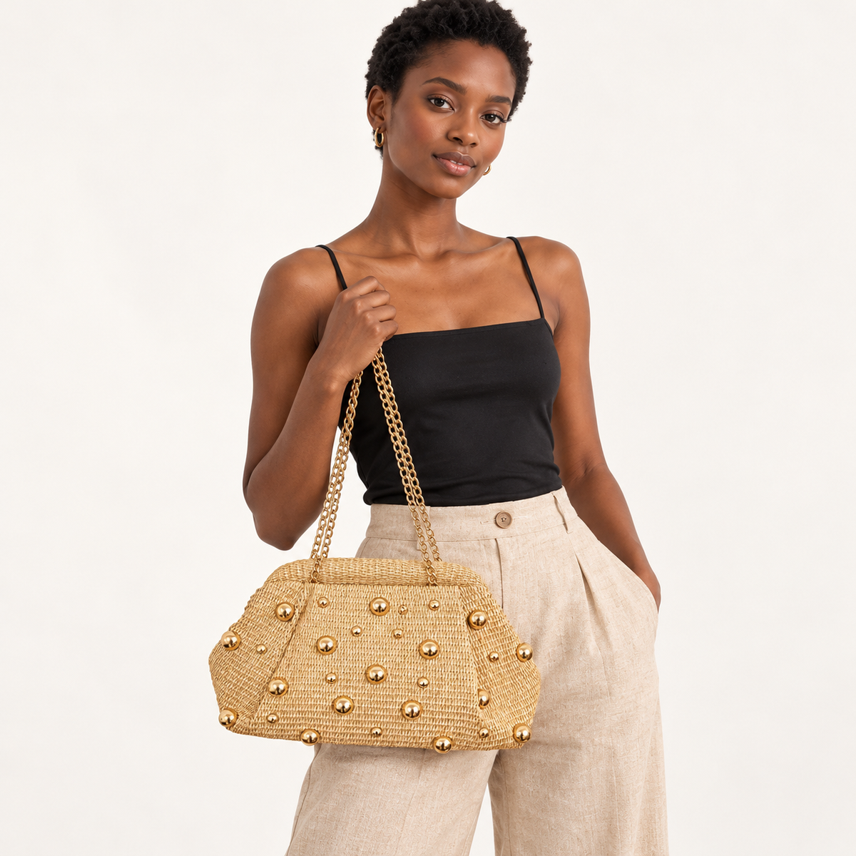 Woman carrying the Gold Stud Woven Clutch in natural / gold studs, studio styling