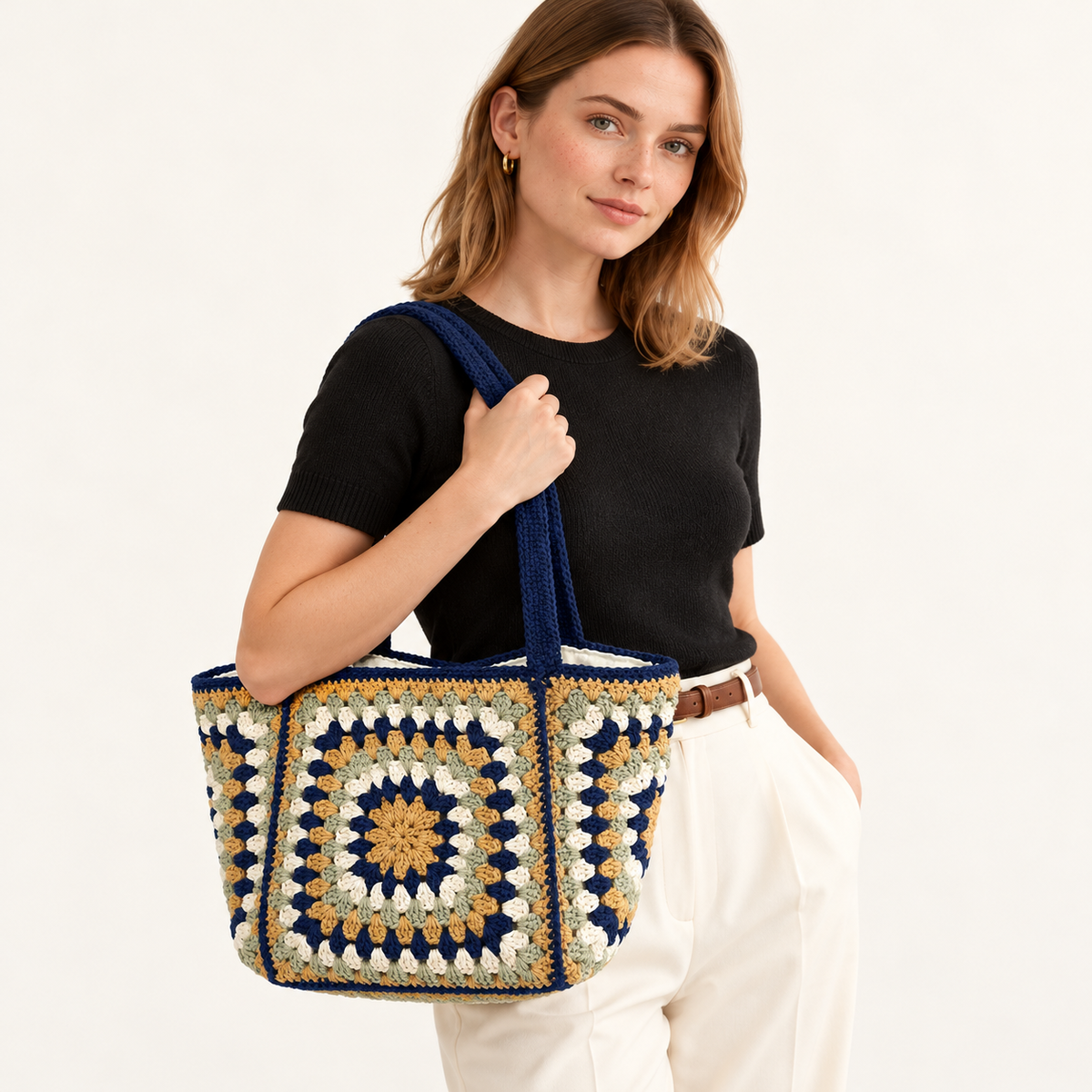 Woman carrying the Navy Granny Square Cotton Tote in navy / cream / yellow, studio styling